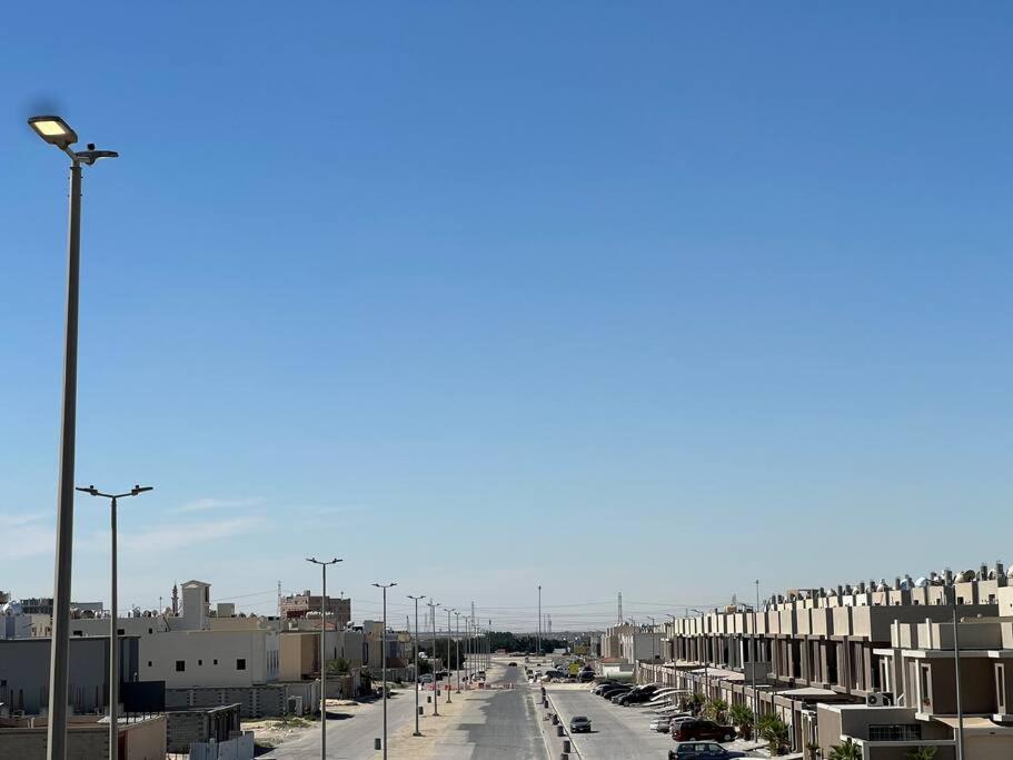 uma rua da cidade com carros estacionados e edifícios em Brand new apartment em Al Fayşalīyah