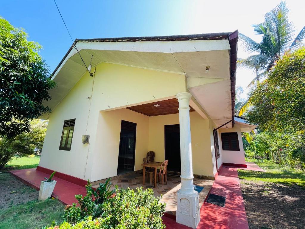 a small house with a porch and a table at Rathna Villas in Bentota