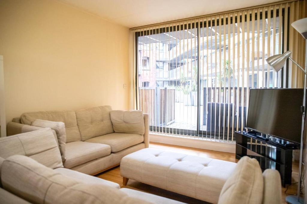 a living room with a couch and a tv at Leeds Vibrant 2 Bedroom Sleeps 4 in Leeds