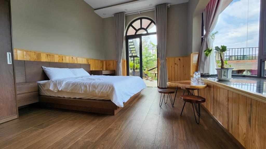 een slaapkamer met een bed, een tafel en een raam bij THẢO NGUYÊN VILLA BẢO LỘC in B'su M'rac