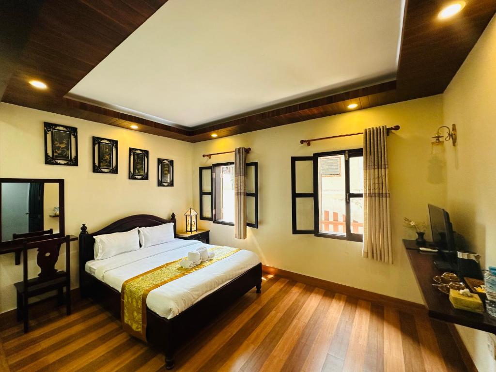 a bedroom with a bed and two windows at Villa Ban Pakham Hotel in Luang Prabang