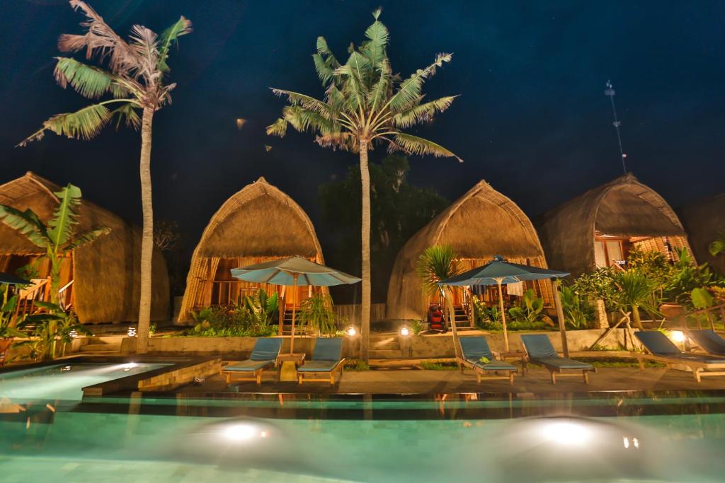 a resort with a swimming pool with chairs and umbrellas at Sunset Coin Lembongan in Nusa Lembongan