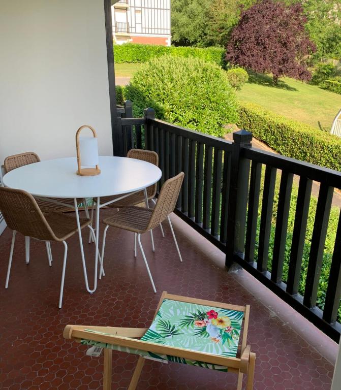 un patio avec une table et des chaises sur un balcon dans l'établissement Apartment with swimming pool - near train station, à Villers-sur-Mer