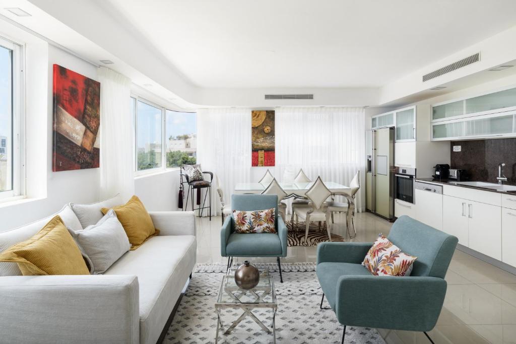 a living room with a couch and chairs and a kitchen at Penthouse with Panoramic View by FeelHome in Tel Aviv