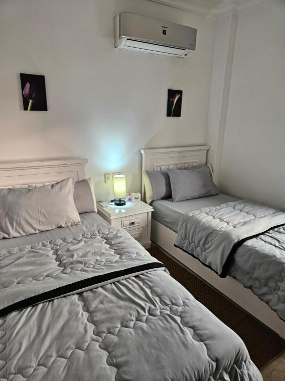 sypialnia z 2 łóżkami i szafką nocną w obiekcie شقة مفروشةومريحةفي مدينتي قريبة من كل الخدمات والحركة w mieście Madinaty