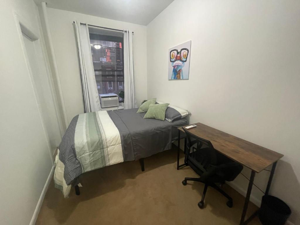 a bedroom with a bed and a desk and a window at Comfy Guest House by Columbus Circle in New York