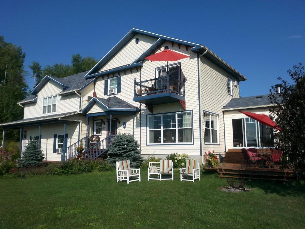 a large white house with chairs in the yard at Domaine de la Baie, Les Suites in Shawinigan