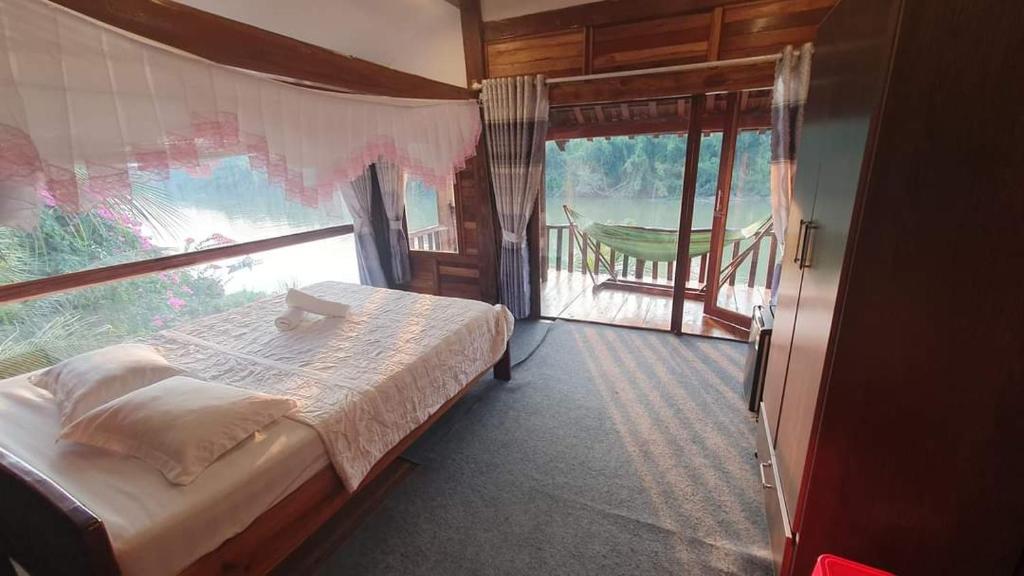 a bedroom with a bed and a large window at Green Bamboo Lodge Resort in Cat Tien