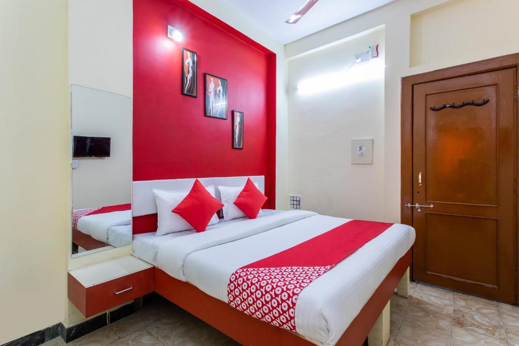 a bedroom with a red wall and a bed at Hotel Santushti in Dewās