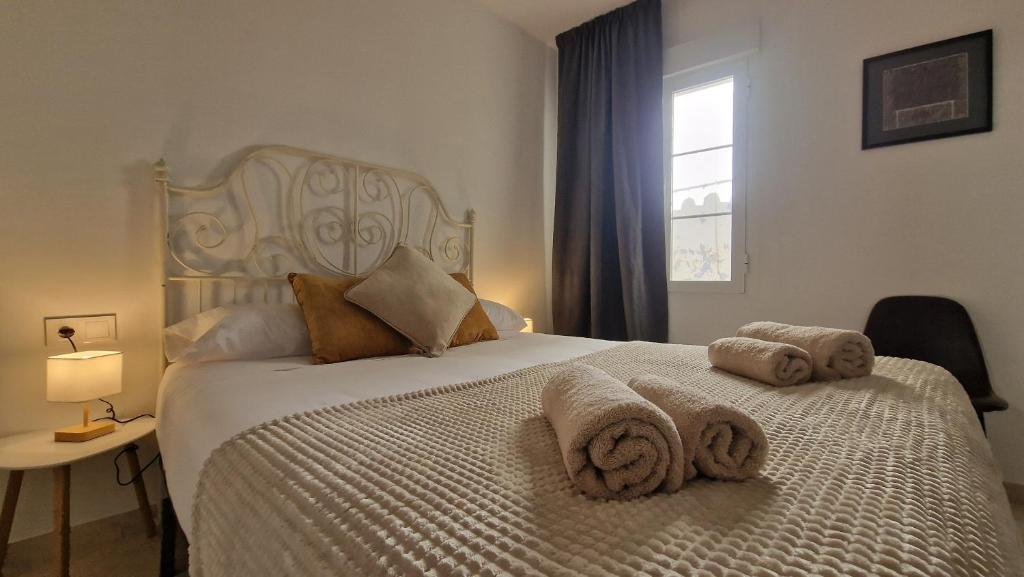 Un dormitorio con una cama blanca con toallas. en DS LealHomes, patio and terrace, en Córdoba