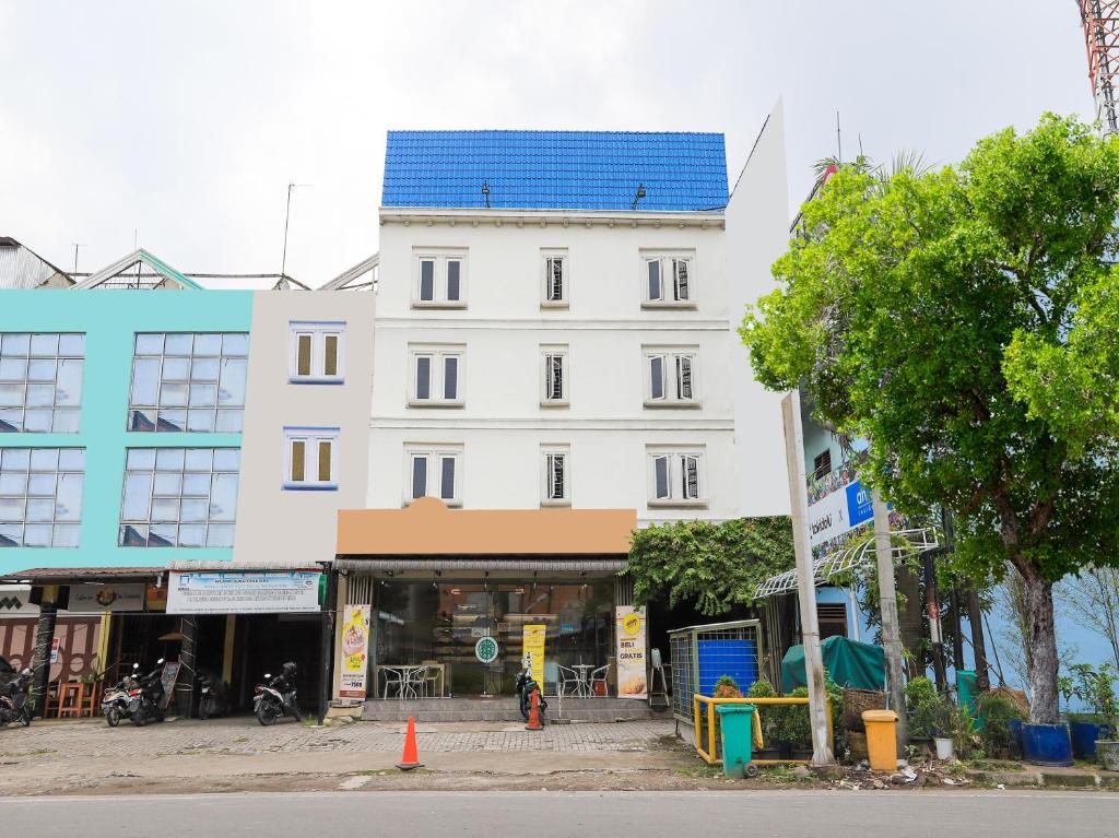 ein weißes Gebäude mit blauem Dach auf einer Straße in der Unterkunft OYO 90021 Tokidoki X Ah123 Residence in Medan