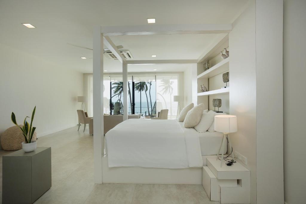 a white bedroom with a white bed and a table at Green Turtle Villa by The Serendipity Collection in Bentota