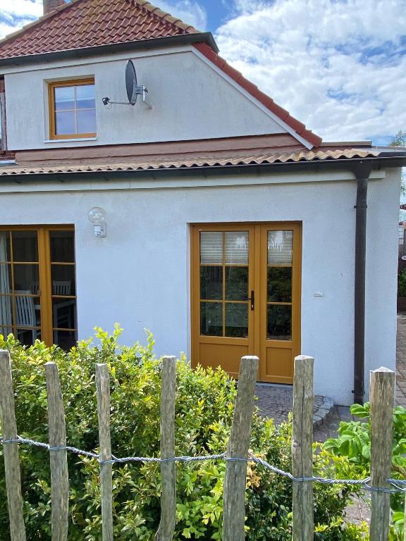 a white house with a yellow door and a fence at Ferienhaus Leuchtturm in Fehmarn