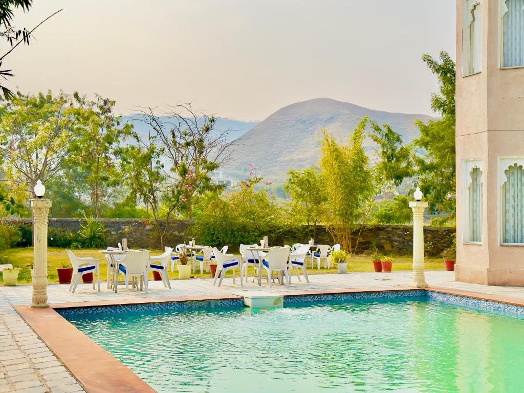 una piscina con sedie e tavolo e una piscina di Jag Aravali Resort Udaipur- Experience Nature away from city Hustle a Udaipur