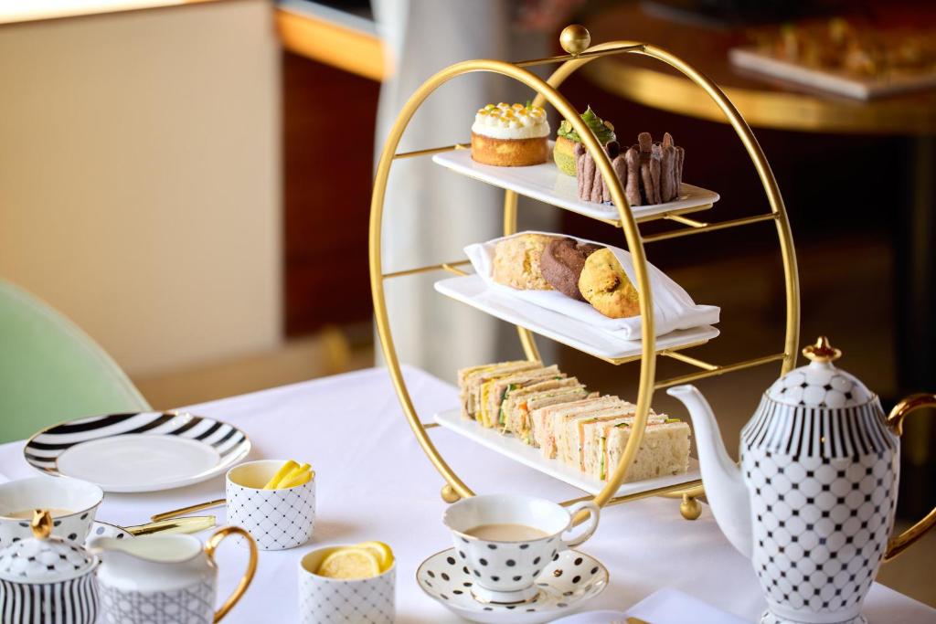 An afternoon-tea setting with tiered pastries and sandwiches, patterned china and a gold tea stand.