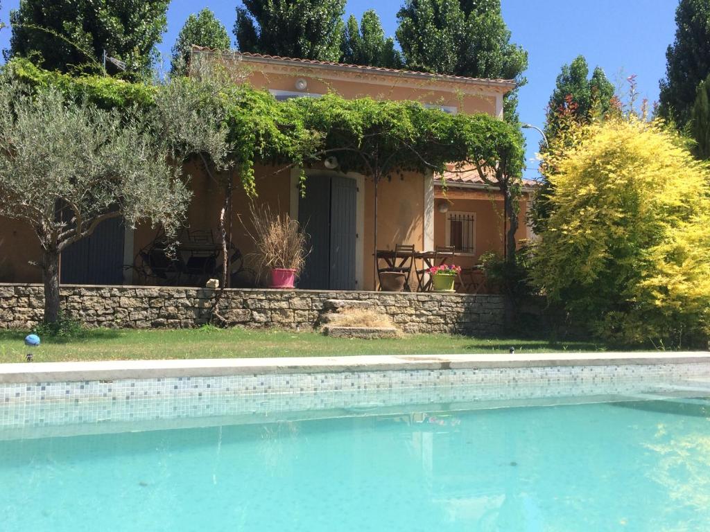 a villa with a swimming pool in front of a house at Belle maison provençale au pied du Mont Ventoux in Caromb