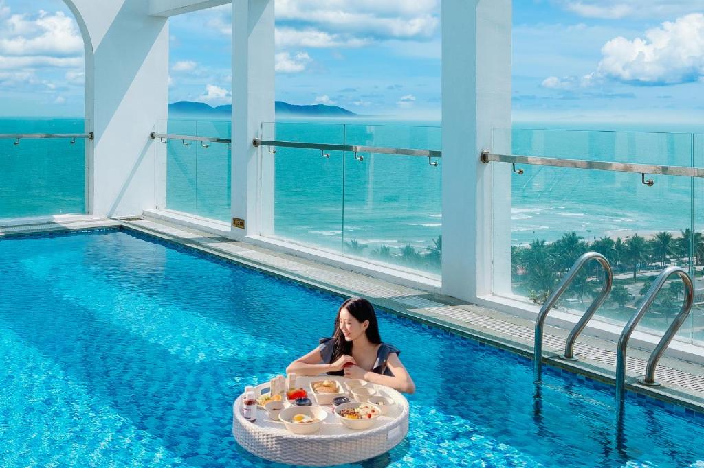 a woman sitting in a pool with a tray of food at Tuyet Son Hotel (TS Ocean Hotel) in Da Nang