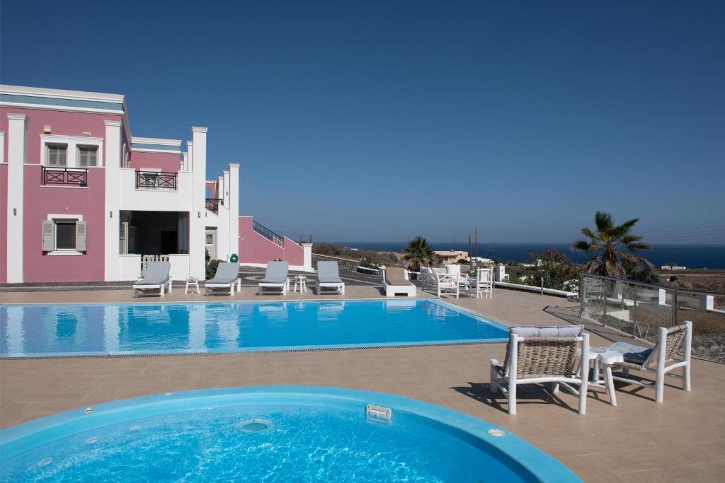 una gran piscina con sillas y una casa en Rose Suites en Vourvoulos