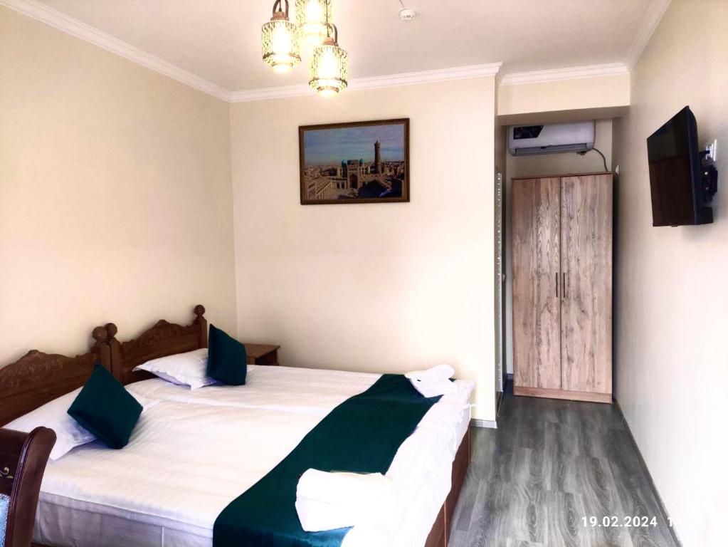 a hotel room with two beds and a television at Antique Hotel Rizvan in Bukhara