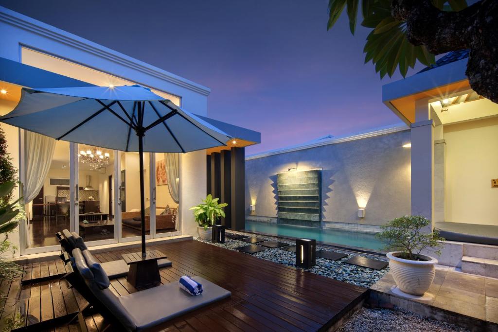 un patio al aire libre con sombrilla y piscina en The Seiryu Boutique Bali Villas, en Seminyak