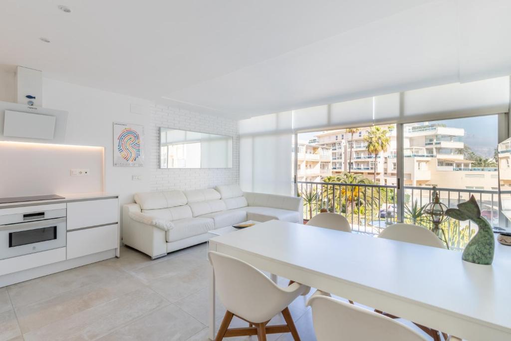 a kitchen and living room with a white table and chairs at Albir Playa in L’Alfàs del Pi