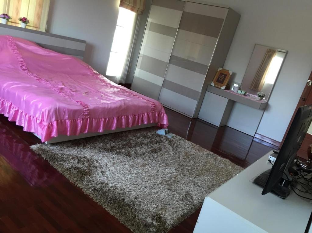 1 dormitorio con cama rosa y alfombra en Wan Ton vacation home, en Nakhon Sawan