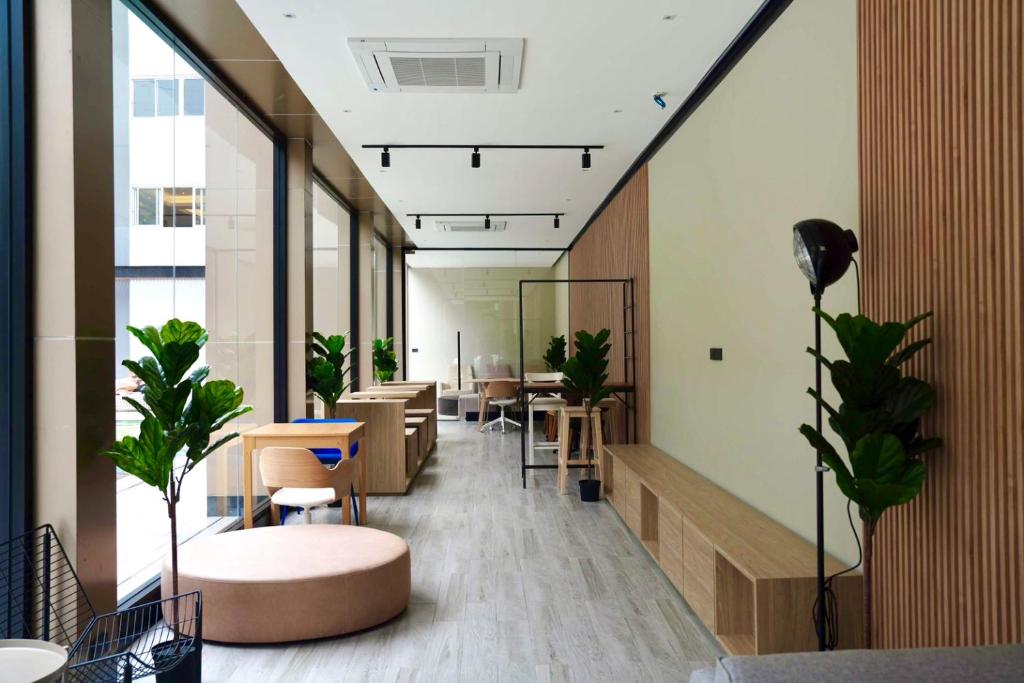 A bright shared workspace combines window seating, small tables, and built-in benches.