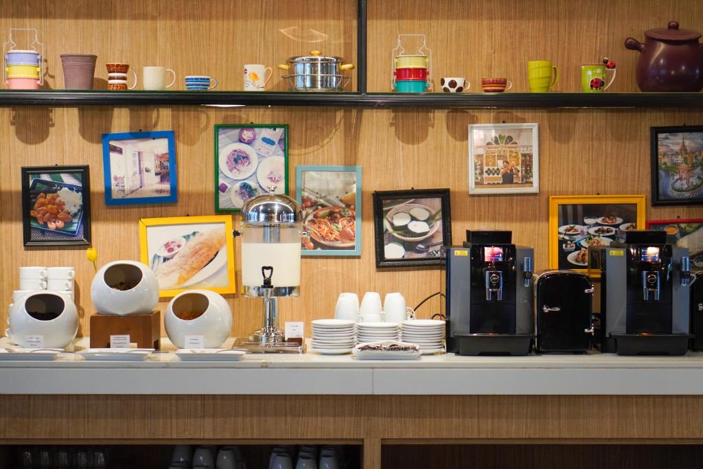 A coffee and drinks station lines a wood-backed counter with multiple machines and tableware.