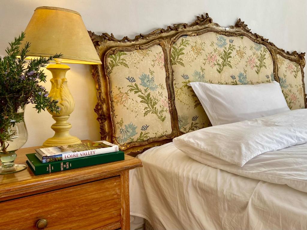 a bed with a table with a lamp and books at Chateau la Bainerie in Tiercé