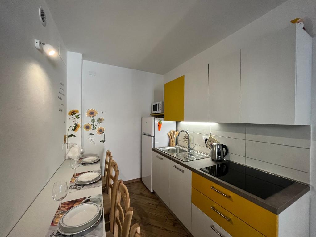 una cocina con armarios blancos y una mesa con sillas. en Borgo Bliss Apartment, en Tenno