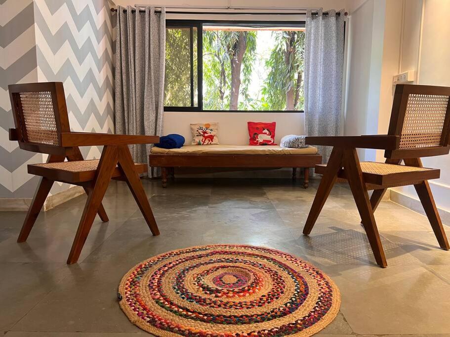 a living room with two chairs and a bench and a window at Home Stay in Mumbai