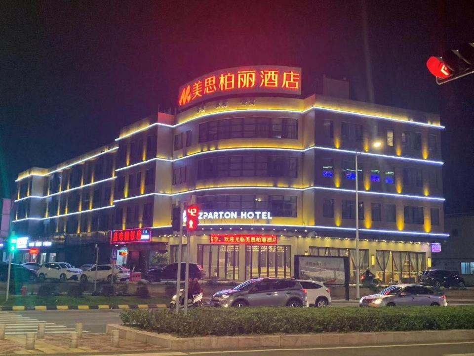 a building with cars parked in front of it at night at MIZPARTON HOTEL - Heshan New Town in Jiangmen