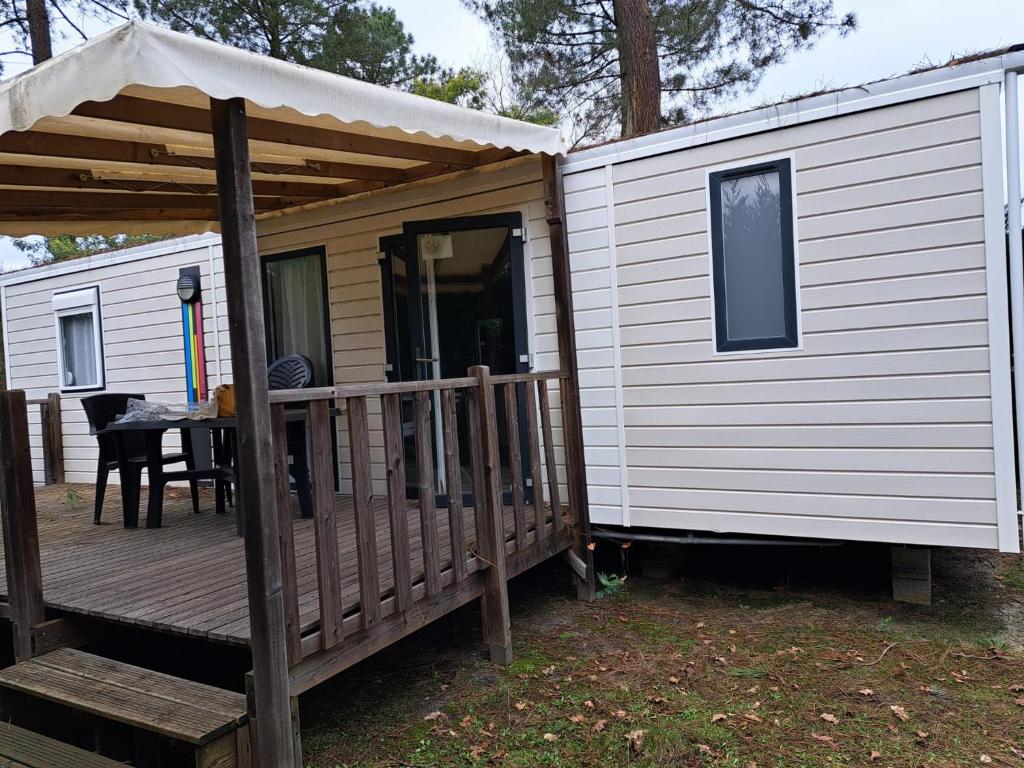 a cabin with a porch and a deck with a table at Camping du Domaine de la Forge in La Teste-de-Buch