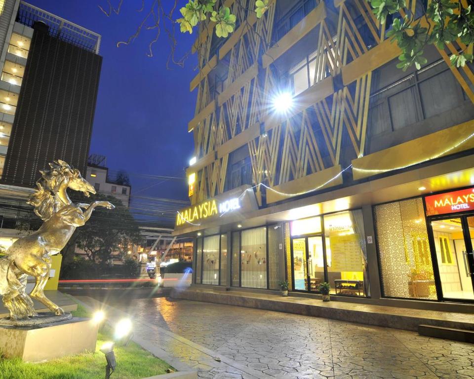 une rue de la ville avec une statue en face d'un bâtiment dans l'établissement Malaysia Hotel Bangkok, à Bangkok