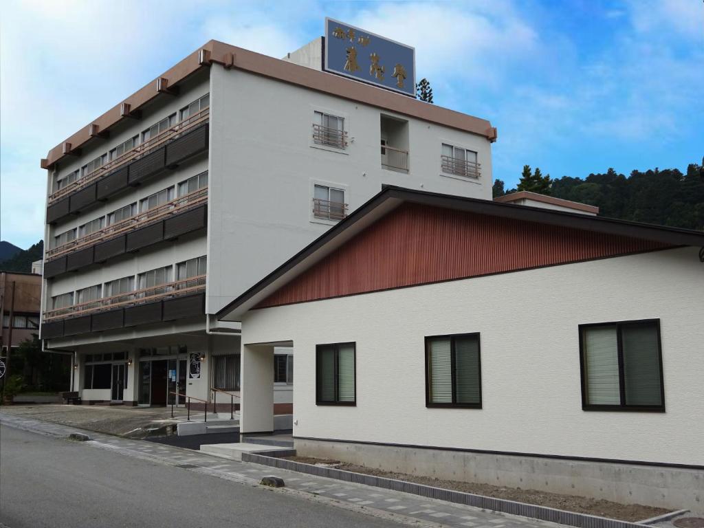 a white building with a sign on top of it at Hotel Harumoto in Nikko