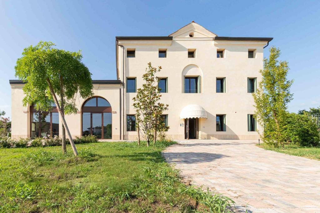 duży biały budynek z drzewem przed nim w obiekcie Residence Superstar w mieście San Martino di Lupari