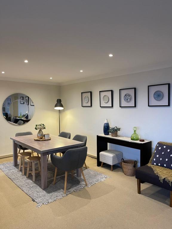 ein Esszimmer mit einem Tisch, Stühlen und einem Spiegel in der Unterkunft Gosfords Best Location with Views in Gosford