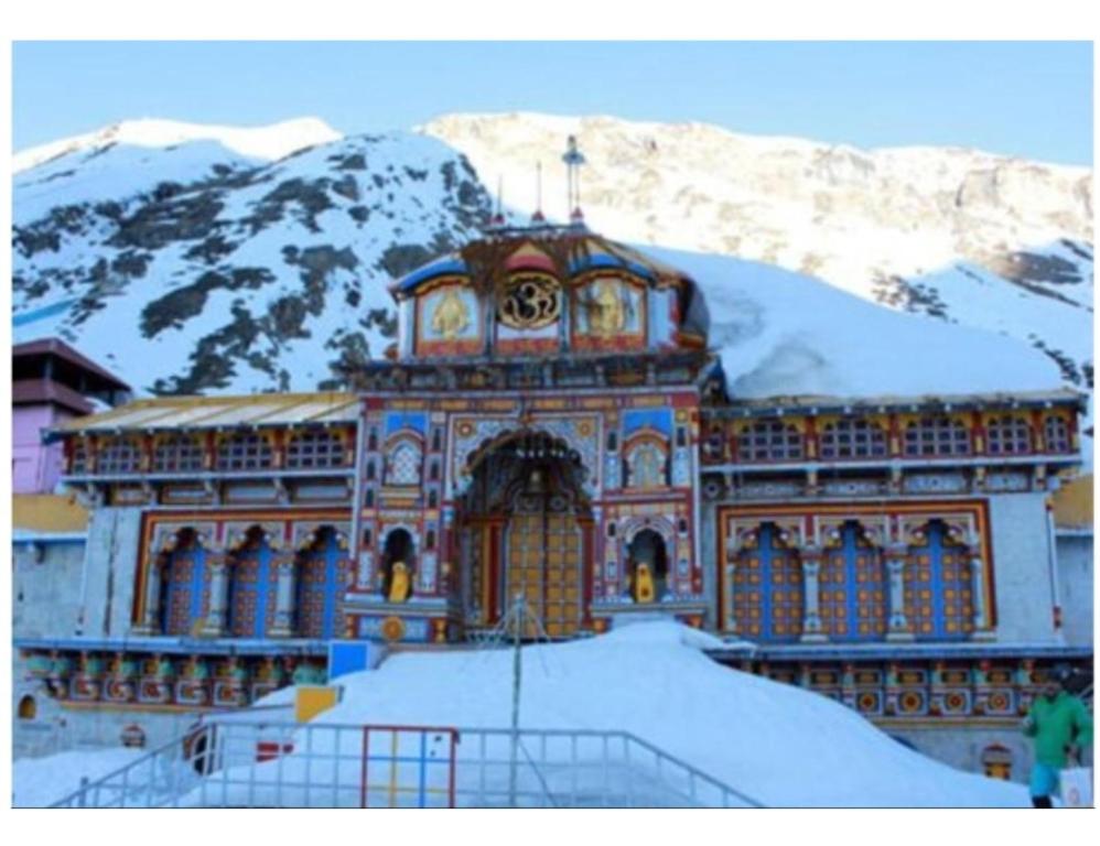 a large building with a clock on it in the snow at Hotel Narmada Bhawan, Badrinath in Badrinath