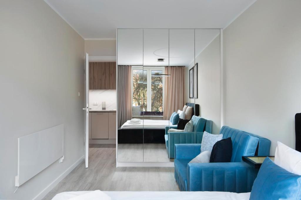 a living room with a blue couch and a kitchen at Elite Apartments Garncarska Classy in Gdańsk