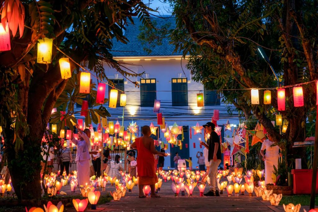 een groep mensen die door een tuin met lantaarns lopen bij PHA NYA RESIDENCE in Luang Prabang