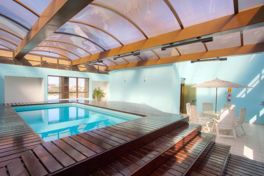 a swimming pool with a balcony and chairs at Bristol Upper Residence Hotel in Curitiba