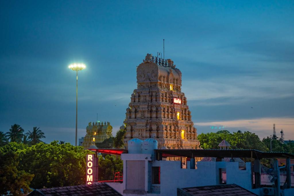 un edificio con una torre de reloj por la noche en Hotel Arya Grand Rameswaram by Nimalan, en Rameswaram