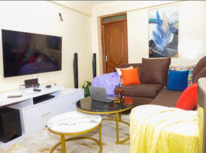 uma sala de estar com um sofá e uma mesa com um computador portátil em Moh Cabins em Nyeri