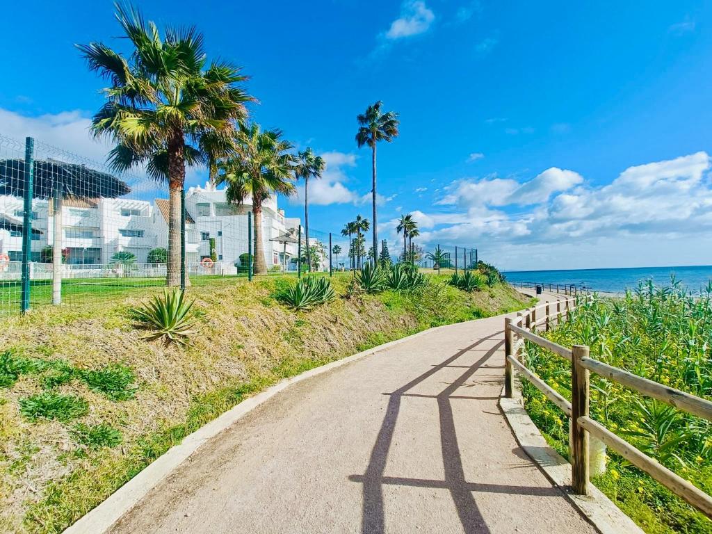 un camino junto a la playa con palmeras en LUXURY Casares del Mar D BJ2, en Casares
