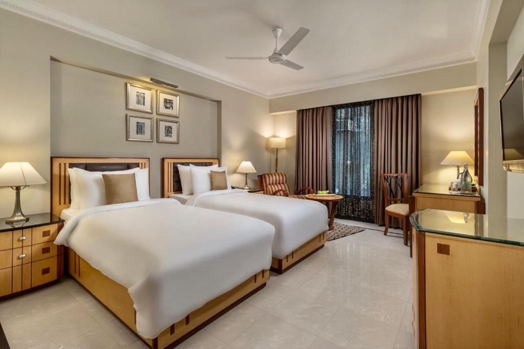 a hotel room with two beds and a desk at Sarovar Portico Kalupur Ahmedabad in Ahmedabad