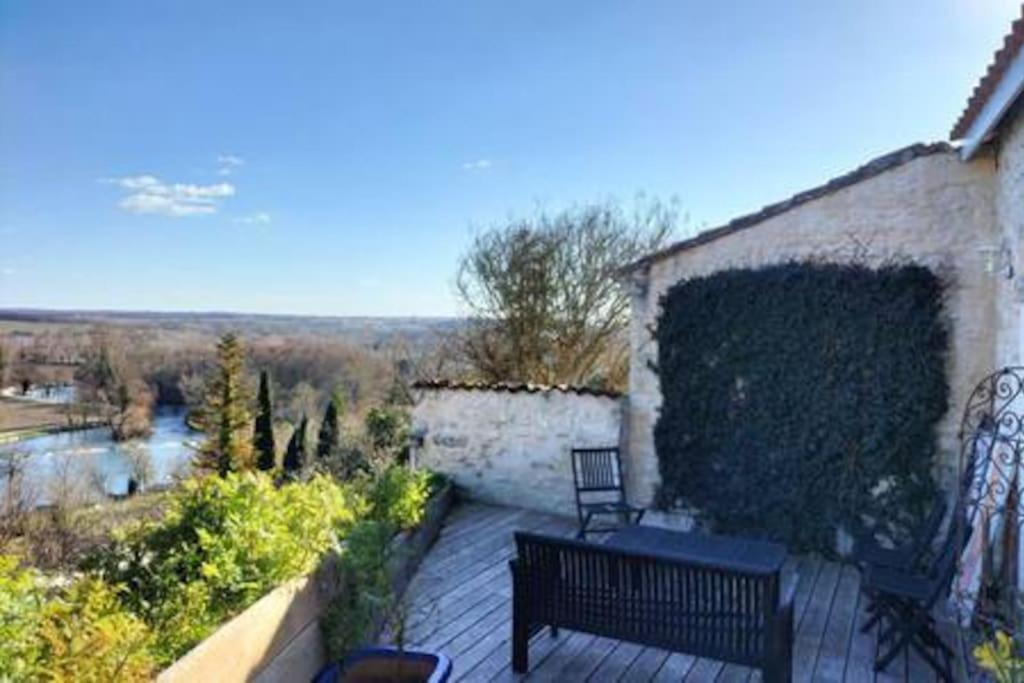 une terrasse en bois avec un banc et une vue sur une rivière dans l'établissement La Chabourne des remparts, à Saint-Simeux