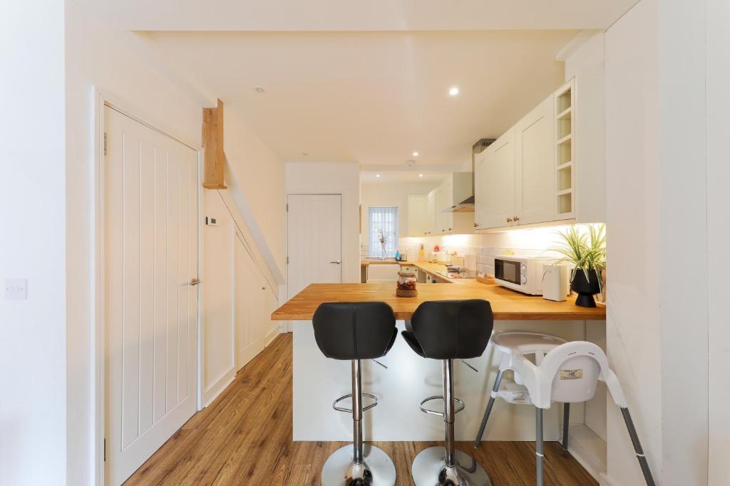 a kitchen with white cabinets and a counter with stools at Hythe Townhouse Retreat in Kent