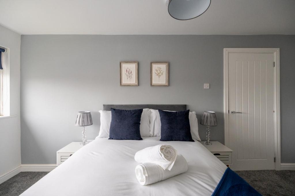 um quarto com uma grande cama branca com almofadas azuis em Woodham House By Horizon Stays em Stockton-on-Tees