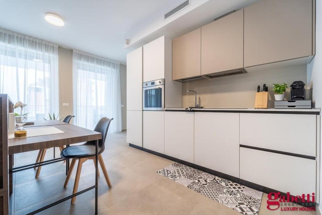 cocina con armarios blancos y mesa de madera en Stilicone 15 - Luxury apt 4D, en Milán