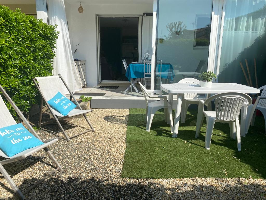 d'une terrasse avec une table blanche et des chaises sur gazon. dans l'établissement Les Baigneuses Pontaillac T2 jardin piscine, à Vaux-sur-Mer
